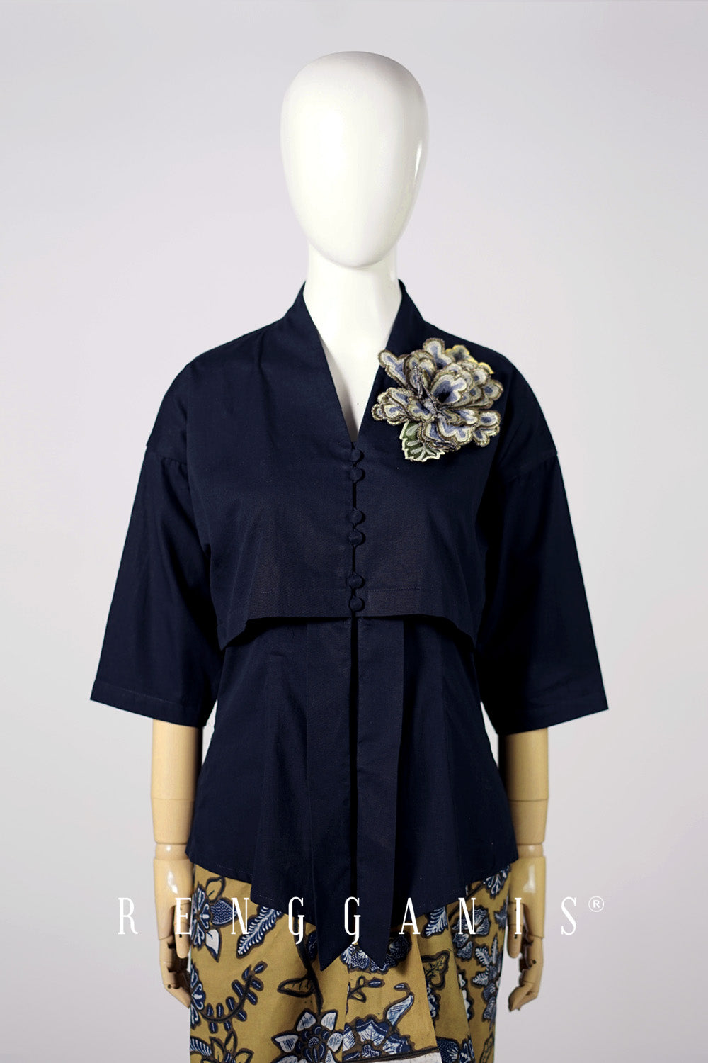 Navy blue top with flower brooch on a mannequin against a white background