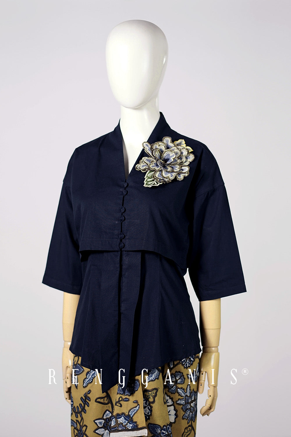 Navy blue top with floral embellishment on a mannequin against a white background